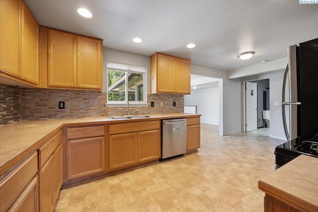 517 S Dawes St, Kennewick, WA 99336 - kitchen with stainless steel dishwasher, a sink, refrigerator, tasteful backsplash, and light countertops