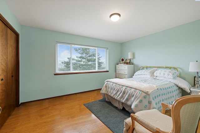 bedroom featuring a closet, light wood-style flooring, and baseboards