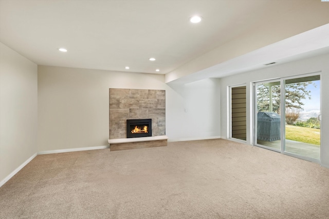 unfurnished living room with carpet, baseboards, a tiled fireplace, and recessed lighting