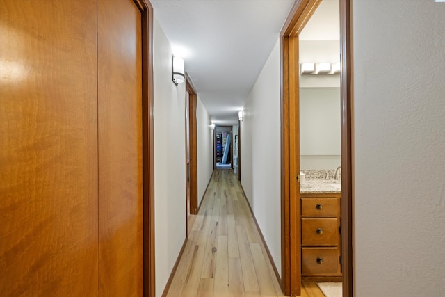 hall featuring light wood-type flooring and baseboards