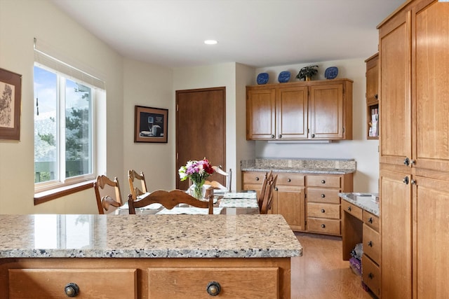 kitchen featuring light stone counters, light wood-type flooring, brown cabinets, and recessed lighting