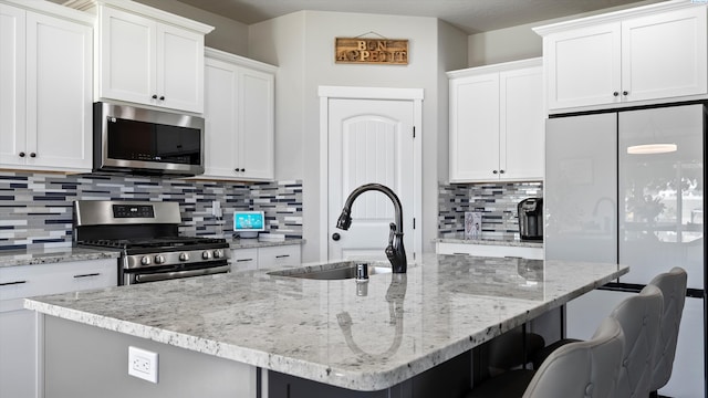 7104 W 31st Pl, Kennewick, WA 99338 - kitchen with stainless steel appliances, a kitchen breakfast bar, tasteful backsplash, and light stone counters