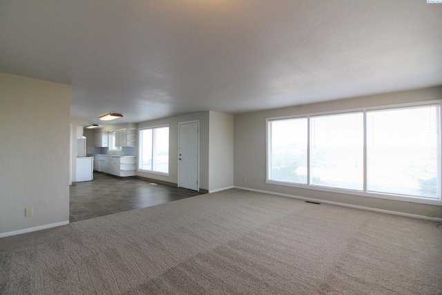 unfurnished living room with carpet floors and baseboards
