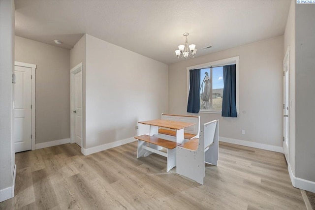 dining room featuring a chandelier, baseboards, visible vents, and light wood finished floors