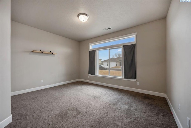 unfurnished room with carpet flooring, visible vents, a textured ceiling, and baseboards