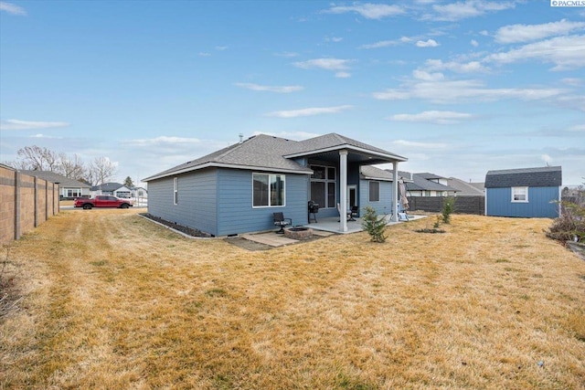 rear view of house with an outbuilding, a yard, a patio area, fence, and a shed