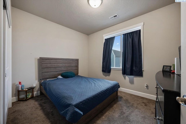 carpeted bedroom featuring a textured ceiling, visible vents, and baseboards