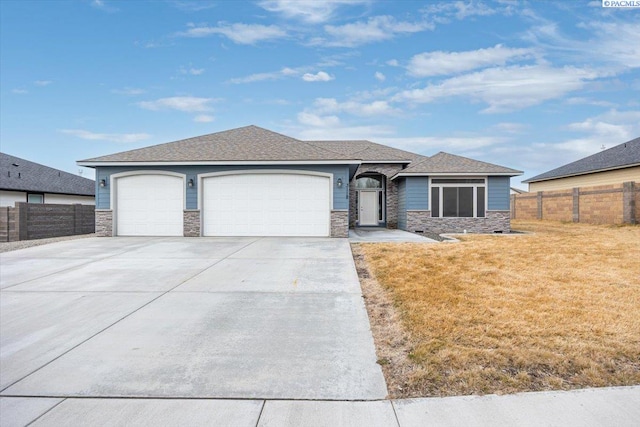 view of front of house with a garage, concrete driveway, stone siding, fence, and a front lawn