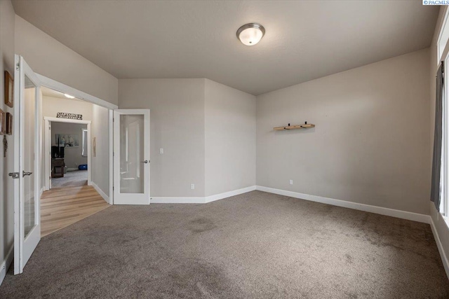 spare room featuring baseboards, carpet flooring, and french doors