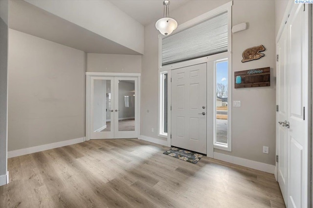 foyer entrance featuring baseboards, wood finished floors, and french doors