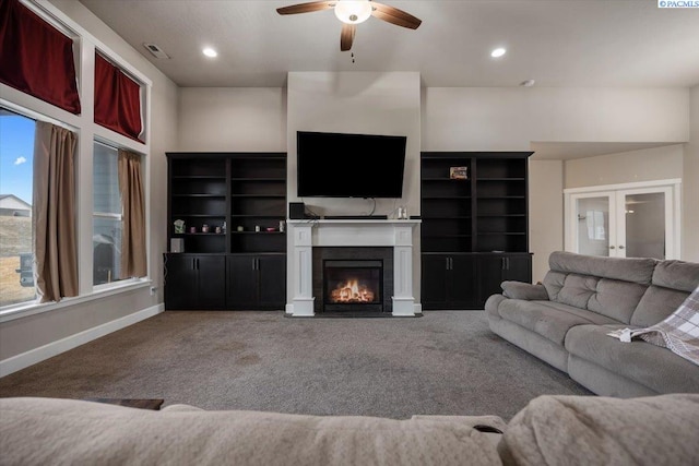 living area featuring carpet floors, a fireplace with flush hearth, visible vents, and baseboards