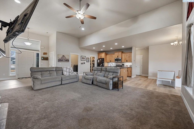 living room featuring recessed lighting, light carpet, a towering ceiling, baseboards, and light wood-type flooring