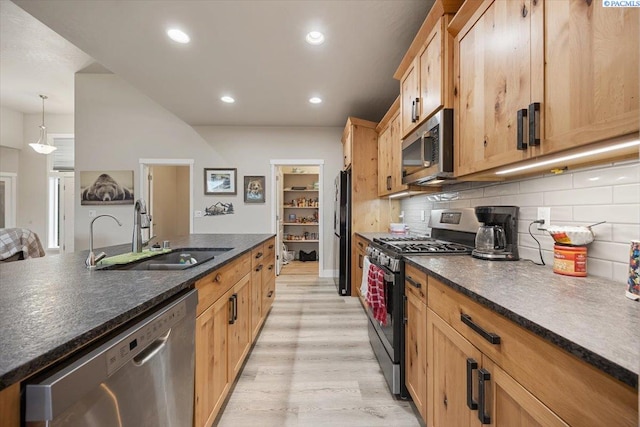 kitchen featuring appliances with stainless steel finishes, a sink, light wood-style floors, backsplash, and recessed lighting