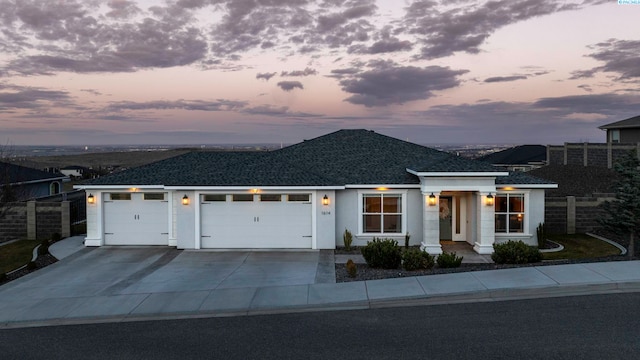 view of front facade with driveway, an attached garage, fence, and stucco siding