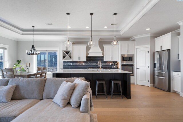 kitchen featuring premium range hood, a tray ceiling, stainless steel appliances, and open floor plan