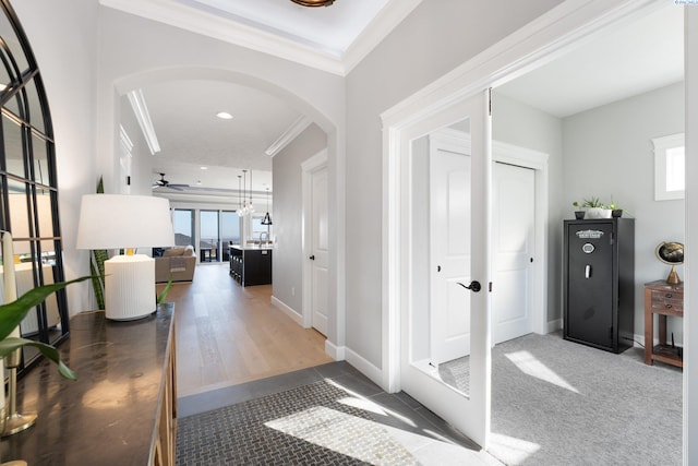 hallway with arched walkways, carpet, crown molding, recessed lighting, and baseboards