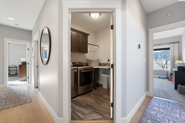 corridor with light wood-style flooring, washer and clothes dryer, and baseboards