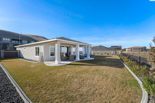 rear view of house with a patio area, a fenced backyard, a yard, and stucco siding