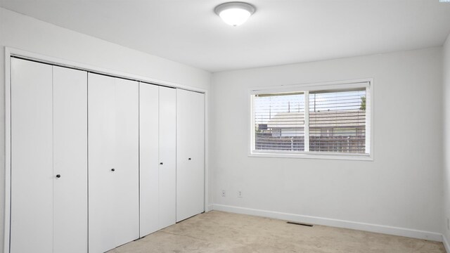 unfurnished bedroom featuring light carpet and a closet