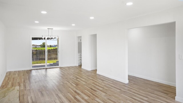 unfurnished room with an inviting chandelier and light wood-type flooring