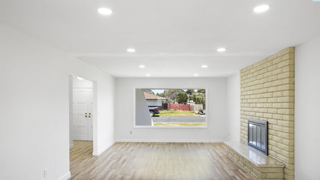 unfurnished living room featuring a fireplace and light hardwood / wood-style floors