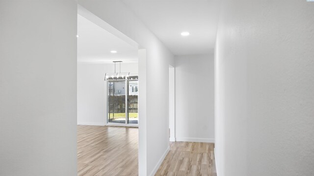 hall featuring an inviting chandelier and light hardwood / wood-style floors