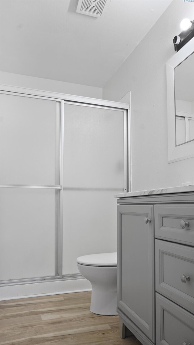 bathroom featuring vanity, hardwood / wood-style floors, an enclosed shower, and toilet