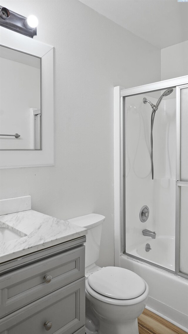 full bathroom with vanity, toilet, combined bath / shower with glass door, and hardwood / wood-style floors