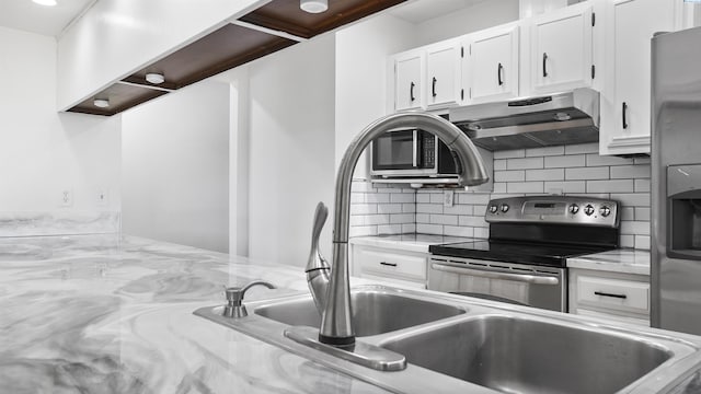 kitchen featuring light stone counters, backsplash, white cabinets, and appliances with stainless steel finishes