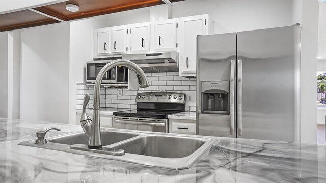 kitchen featuring extractor fan, appliances with stainless steel finishes, white cabinets, backsplash, and light stone countertops