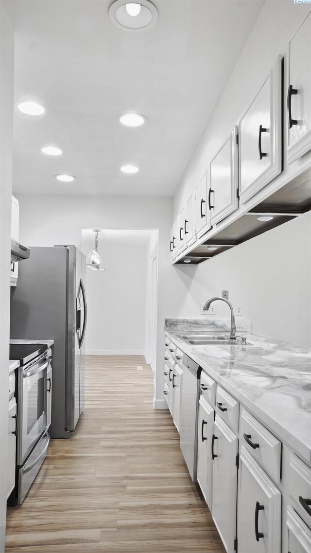 kitchen featuring white cabinetry, exhaust hood, light stone counters, stainless steel appliances, and light hardwood / wood-style flooring