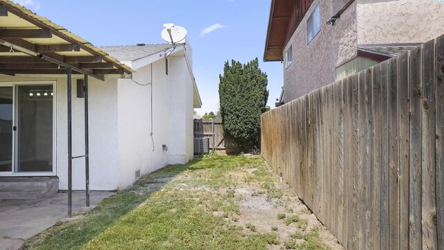 view of side of property featuring central AC unit and a lawn