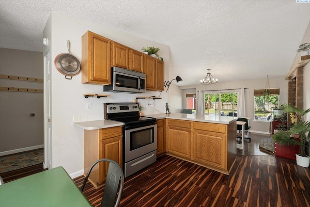 324 S Zinser St, Kennewick, WA 99336 - kitchen with stainless steel appliances, a peninsula, dark wood finished floors, light countertops, and a textured ceiling