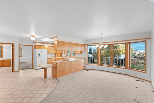 kitchen featuring hanging light fixtures, white fridge with ice dispenser, a notable chandelier, kitchen peninsula, and a textured ceiling