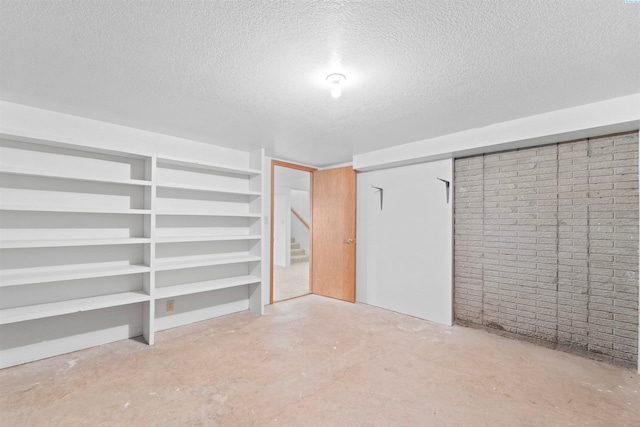 basement with a textured ceiling and brick wall