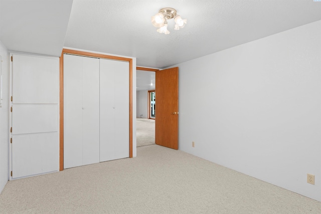 unfurnished bedroom featuring light colored carpet, a closet, and a textured ceiling