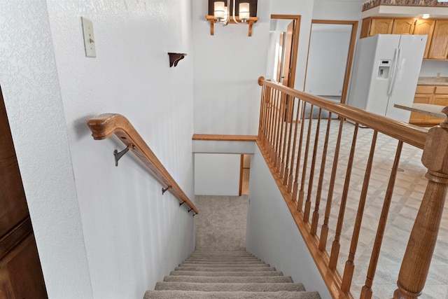 stairway featuring an inviting chandelier and carpet