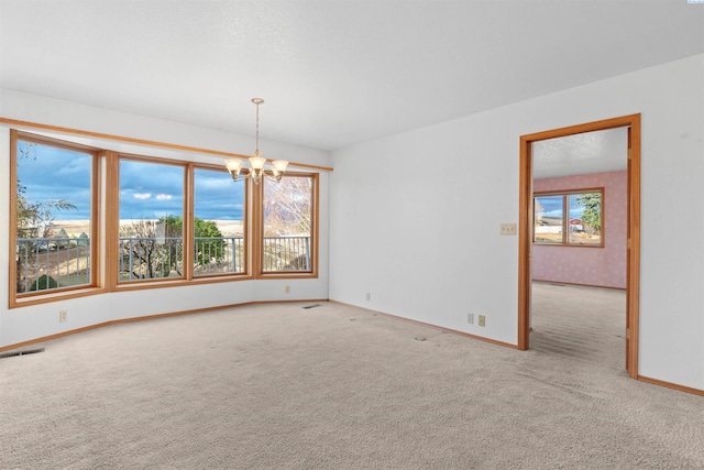 unfurnished room featuring a notable chandelier, a healthy amount of sunlight, and carpet flooring