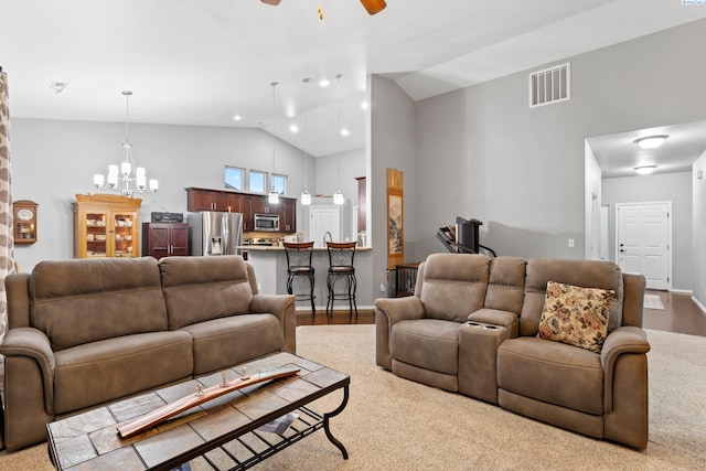 living room with ceiling fan with notable chandelier, high vaulted ceiling, and light hardwood / wood-style floors