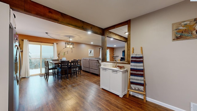 kitchen featuring dark hardwood / wood-style floors, decorative light fixtures, stainless steel fridge, white cabinets, and beam ceiling