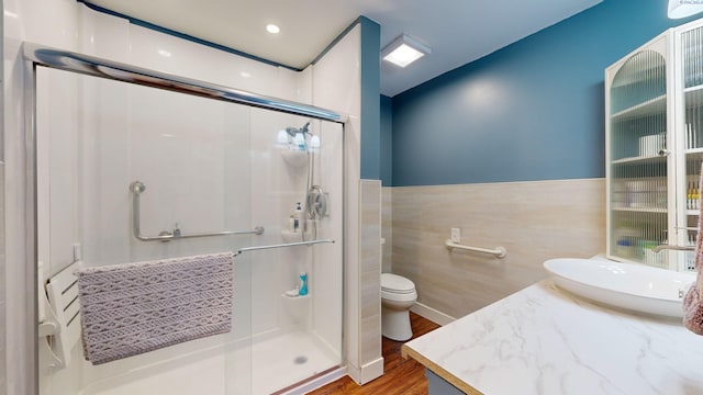 bathroom featuring vanity, hardwood / wood-style floors, a shower with door, and toilet