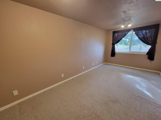 unfurnished room with carpet and a textured ceiling