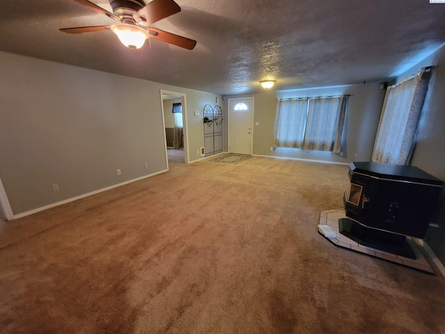 living room featuring ceiling fan, carpet, a wood stove, and a textured ceiling