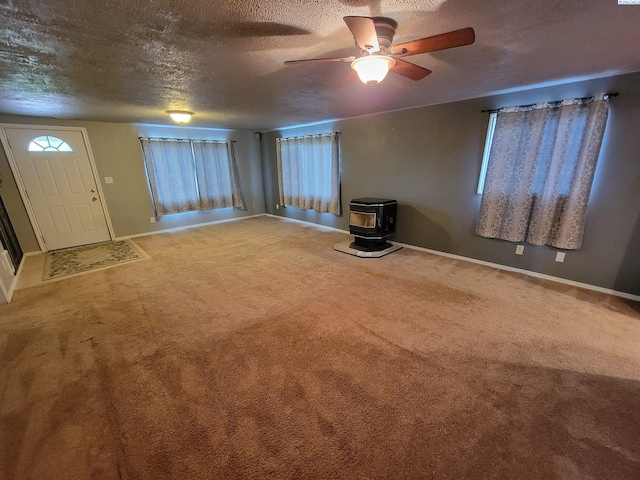 unfurnished living room featuring ceiling fan, carpet floors, a textured ceiling, and a wood stove