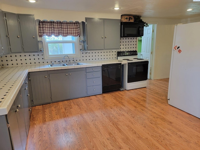 kitchen with gray cabinets, sink, tile countertops, and black appliances