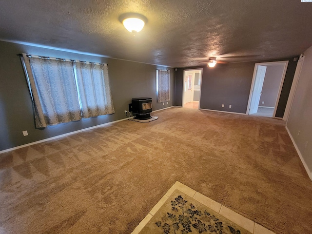 unfurnished living room featuring carpet, a textured ceiling, and a wood stove