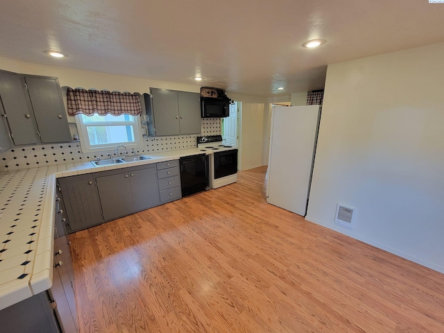 kitchen featuring gray cabinets, sink, light hardwood / wood-style flooring, and black appliances