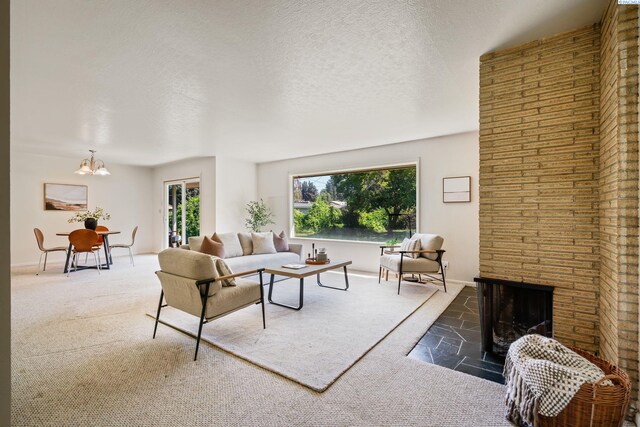 living room with a fireplace, carpet floors, a textured ceiling, and a notable chandelier