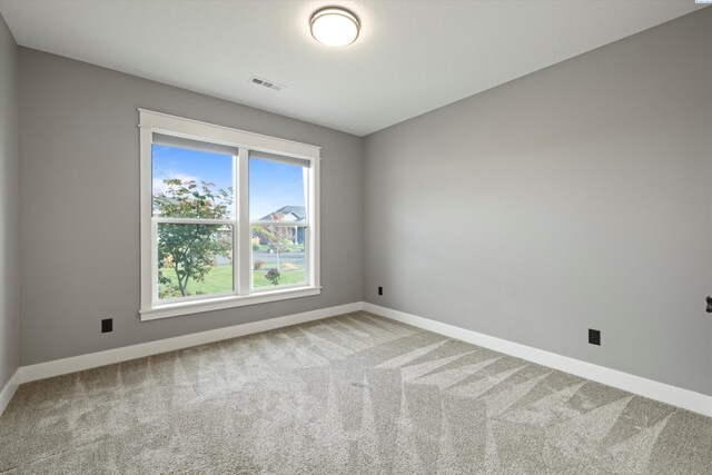 empty room with carpet, visible vents, and baseboards