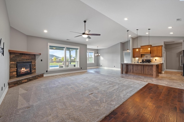 unfurnished living room with a fireplace, recessed lighting, a sink, baseboards, and ceiling fan with notable chandelier